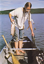
Julie Collins hauls in a whitefish from her gill net on Lake Minchumina, Alaska. The nets are dropped from a canoe daily during the summer. When winter arrives, the lake is covered with a three-foot layer of ice. But once fishing holes have been cut, the nets can be left in the water for up to a week without any spoilage of the catch
